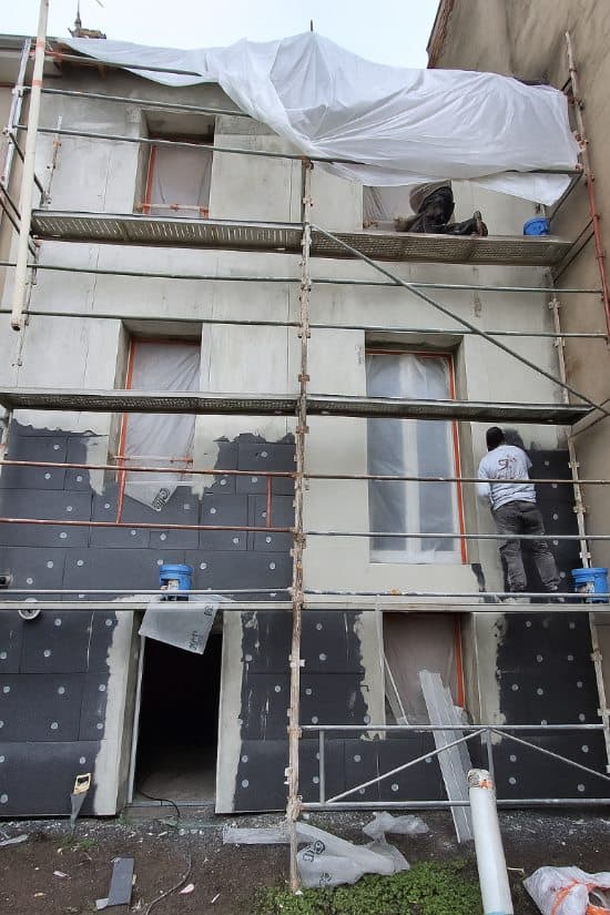 Façade en cours d'enduit sous échafaudage lors d'une ITE